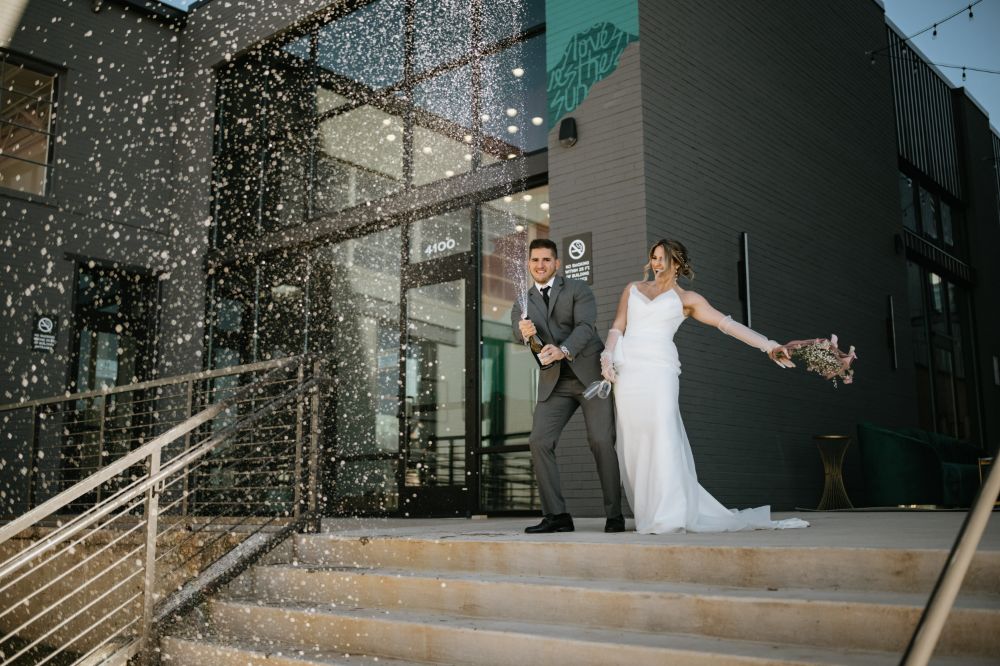 Groom pops a bottle of champagne with his bride in Charlotte, NC