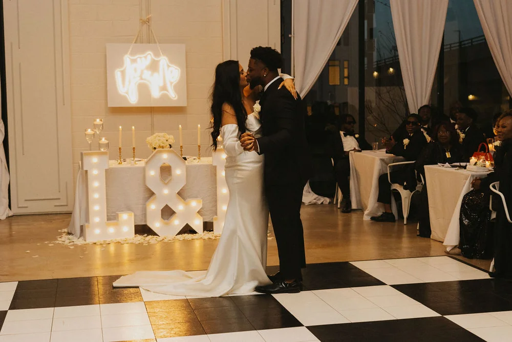 Bride and groom kissing on a black and white checkered dance floor at PINE Charlotte