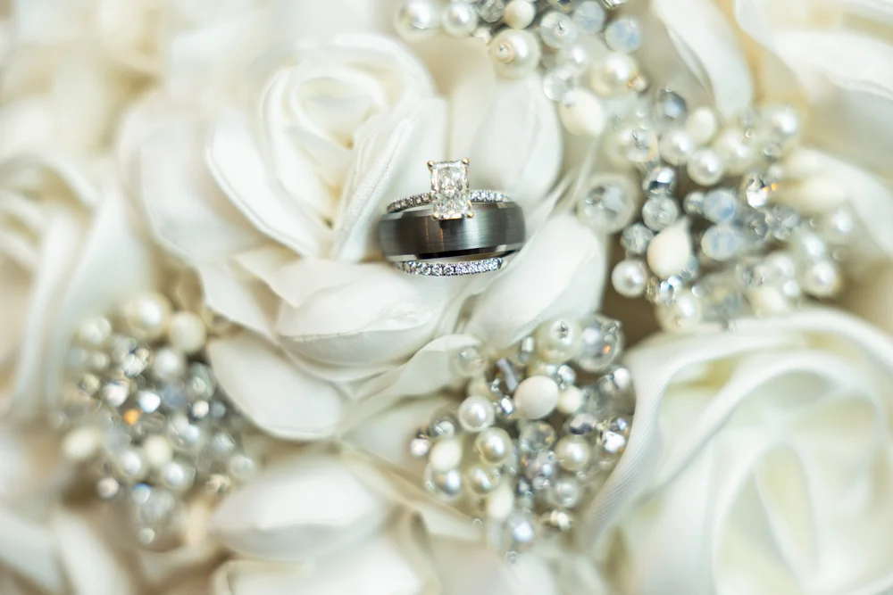 Wedding rings resting on white floral arrangement at Charlotte wedding